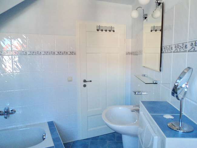 Obere Ferienwohnung: helles Badezimmer mit Wanne, WC, Waschbecken, Spiegel