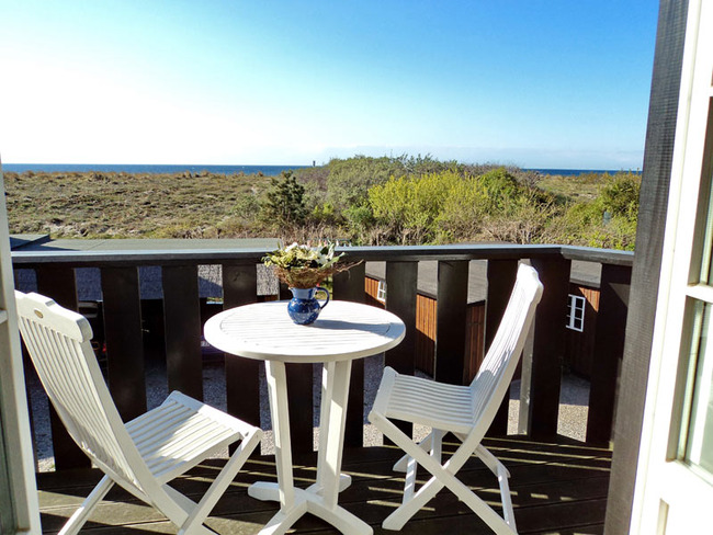Obere Ferienwohnung: Balkon mit rundem Tisch, 2 Stühlen, Blick auf Dünen und Ostsee und den Hof