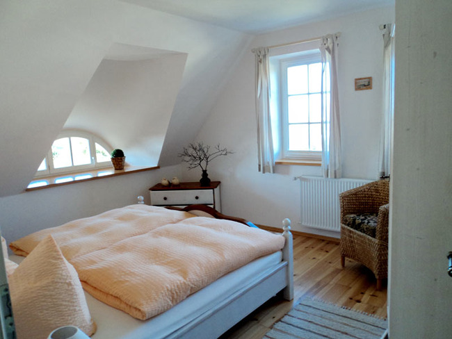 Obere Ferienwohnung: Schlafzimmer mit Doppelbett, Kleiderschrank, Stuhl, Kommode und 3 Fenstern