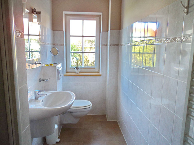 Untere Ferienwohnung - helles Badezimmer mit Fenster, WC, Waschbecken und Spiegel