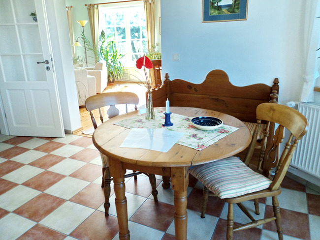 Untere Fewo - Küche mit rustikalen Möbeln: runder Tisch, 2 Stühle, Bank und Durchgang zum Wohnzimmer