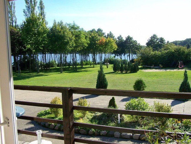 Ferienwohnung für 4 Personen - Ausblick vom Balkon auf den Garten mit Spielplatz und den See